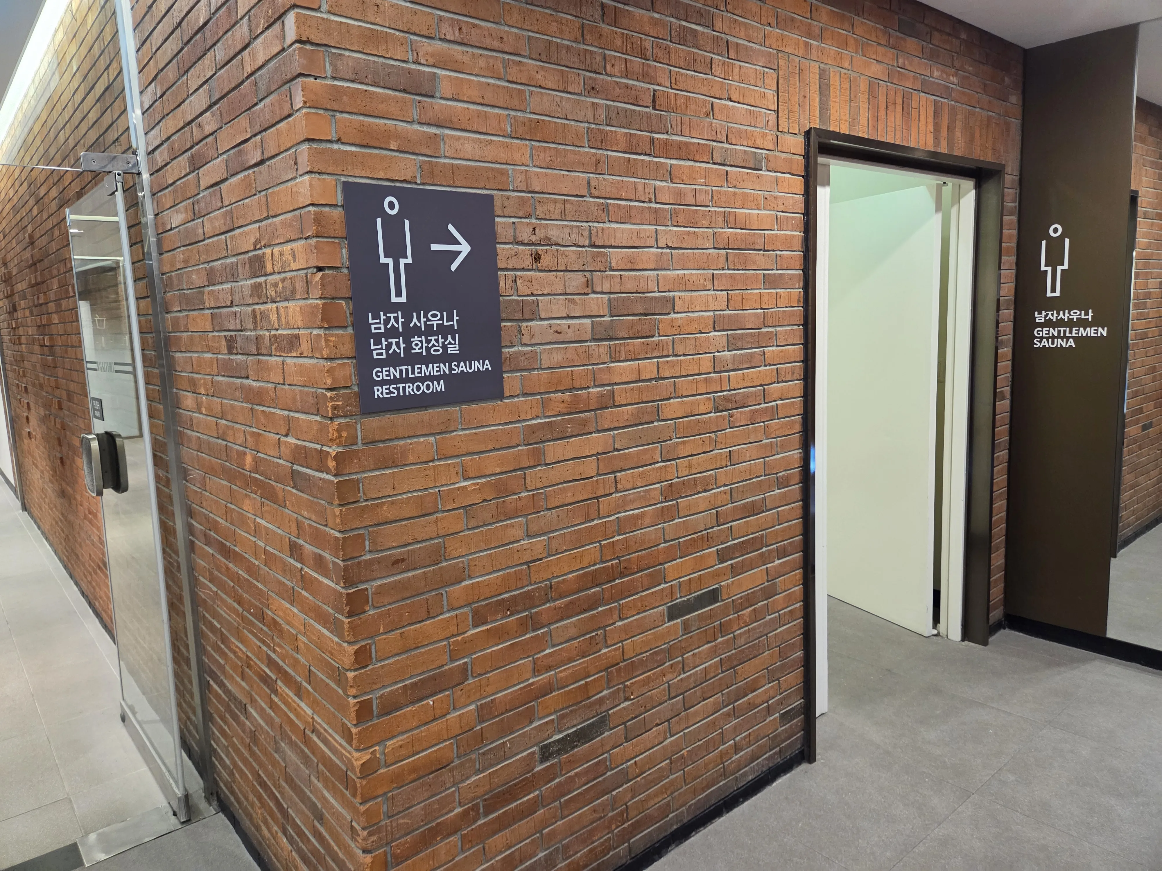 남자 사우나 입구 벽돌벽 안내 사인