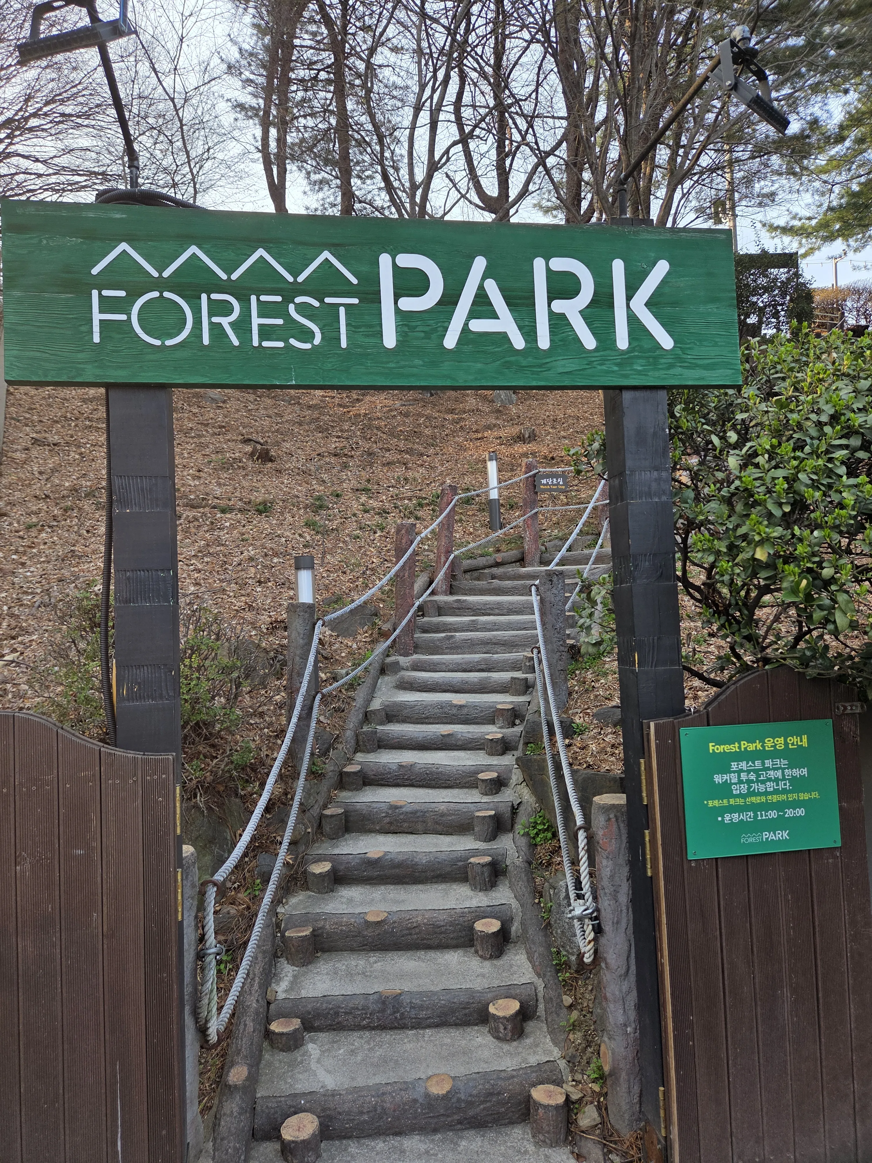 FOREST PARK 초록색 입구 사인과 나무 계단