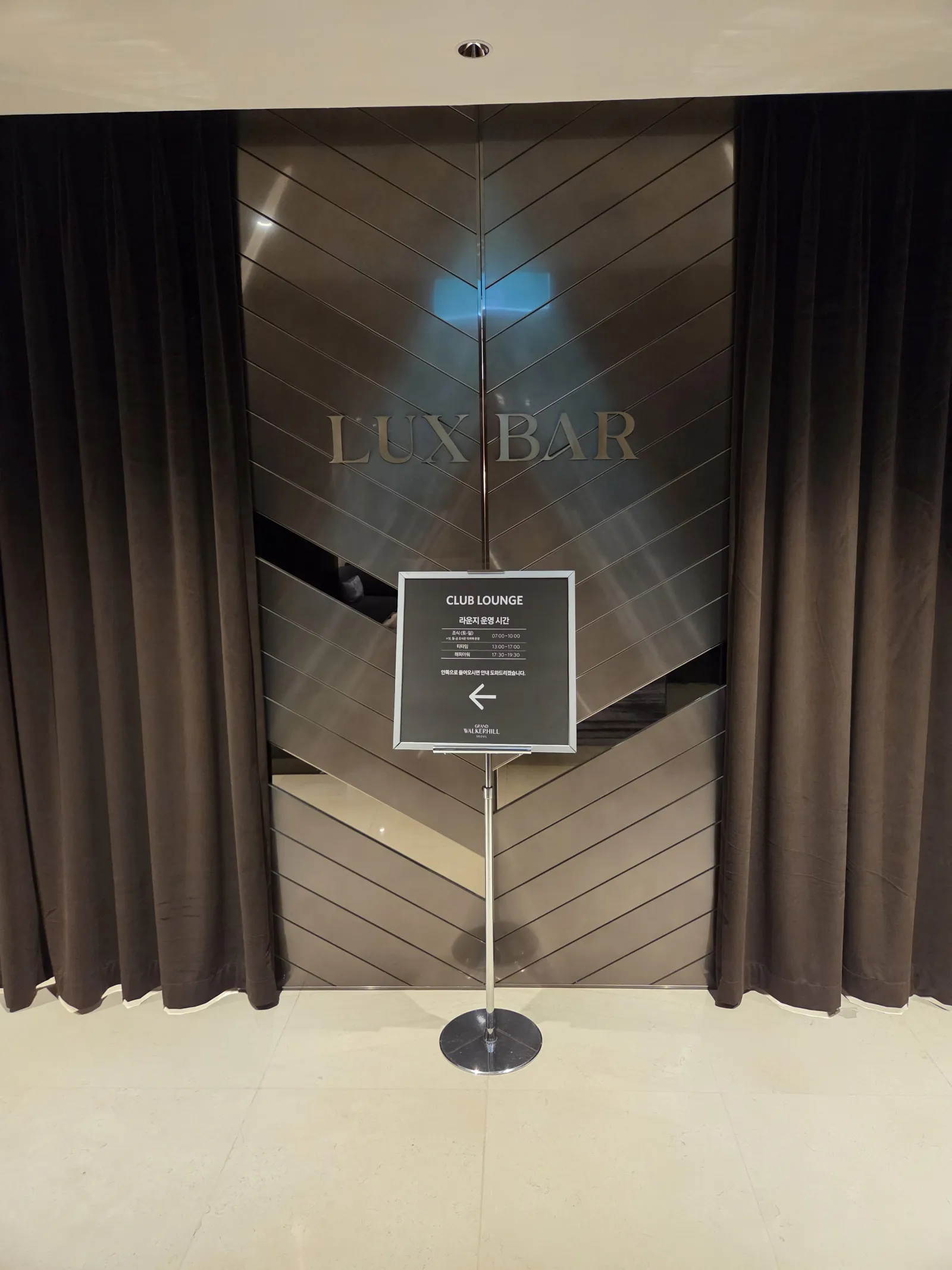 LUXE BAR 입구와 클럽 라운지 운영시간 안내 스탠드